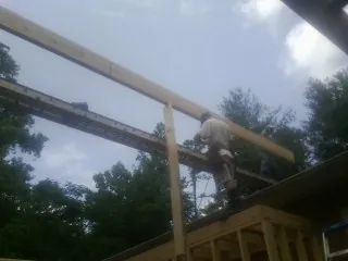 Carpenter setting a ridge beam over a new addition frame — Ice Dam Removal by Roofing Brothers in Alden