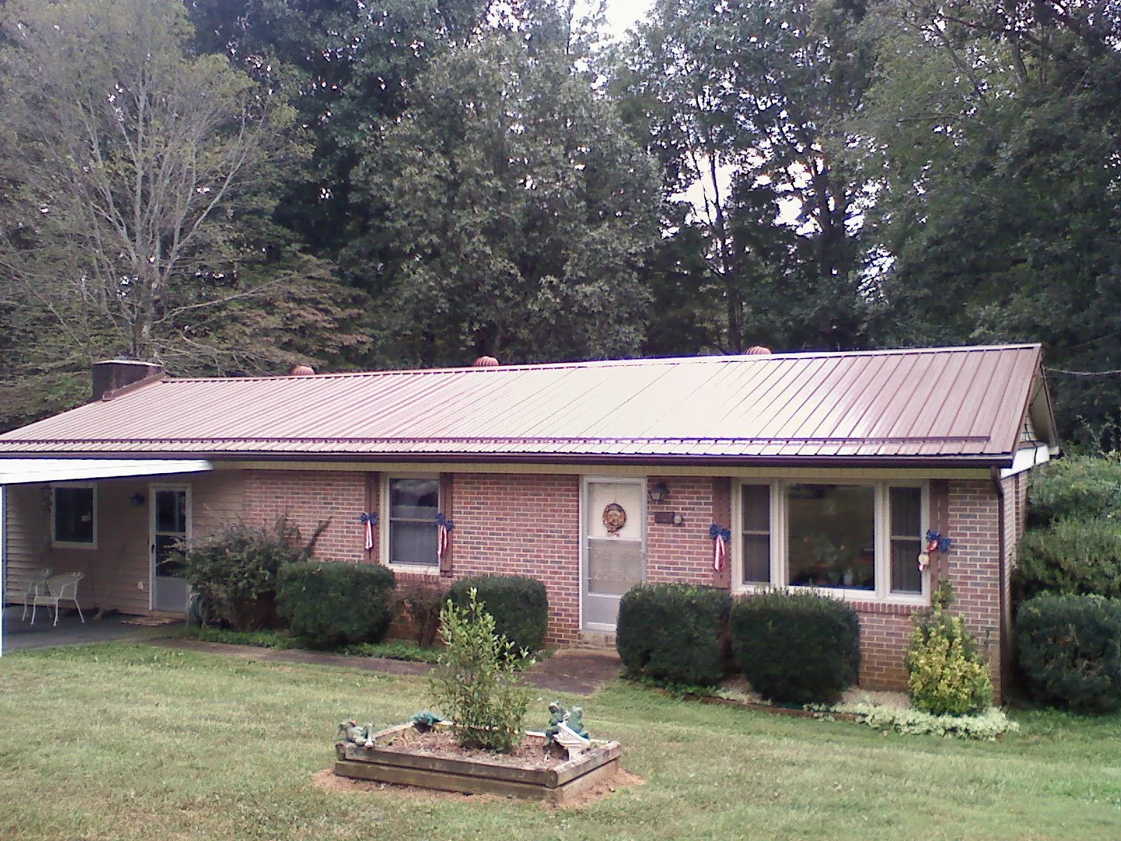 Bronze metal roof on a brick ranch home with a carport in Alden